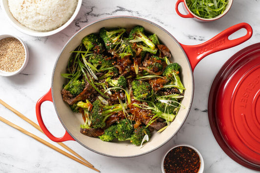 A Le Creuset Cassadou in the color Cerise filled with Hot Honey Beef and Broccoli.