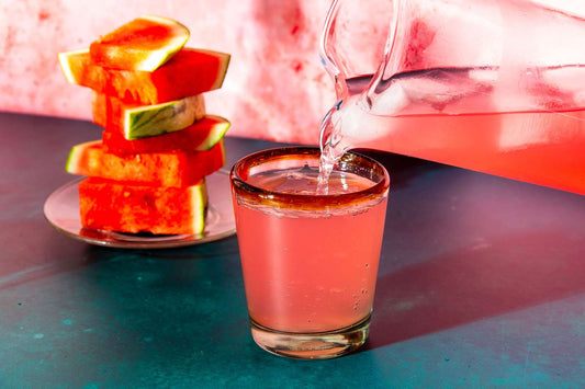 A glass of iced Watermelon Lime Agua Fresca garnished with a lime wedge.