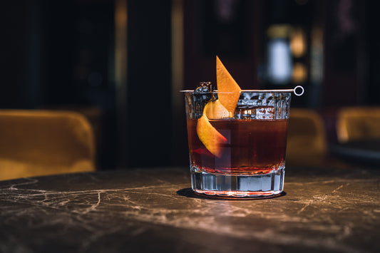 An Old Fashioned glass with a dark liquor and orange peel garnish.