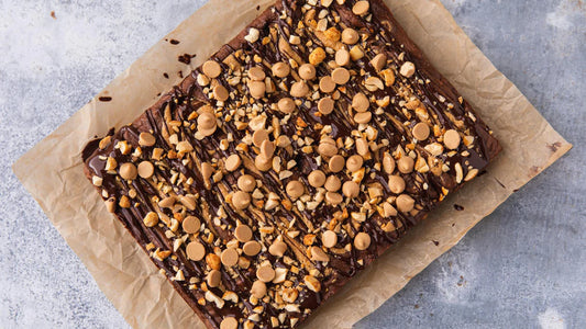 A slab of peanut butter brownies on a sheet of parchment paper, fresh from the oven