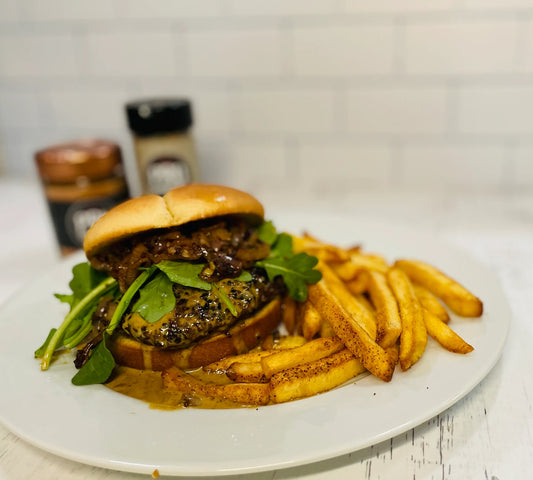 A burger topped with caramelized onions, arugula, and a sourdough bun.