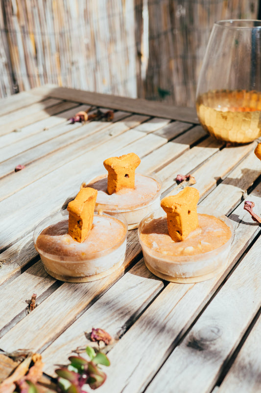 Three small cups filled with frozen dog ice cream, topped with a dog bone treat.